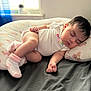 baby, sleeping, infant, onesie, socks, pillow, butterfly_pattern, bed, blanket, curtains, window, natural_light, peaceful, indoor, child, person, soft_light, relaxation, cute, rest