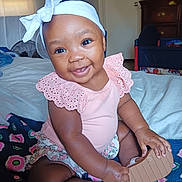 Aliyah joined the competition — help win amazing prizes! baby, child, smiling, headband, pink, clothing, sandal, blanket, indoor, furniture, bed, happy, cute, person, portrait, skin, hand, footwear, dressed, seat