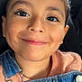 child, face, smile, portrait, denim_overalls, clothing, person, happy, young, casual_wear, car_seat, seat, closeup, eyelashes, skin, button, fabric, head, cute, indoors