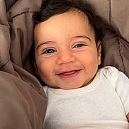 Naïm participe au concours pour gagner de l'argent avec cette photo : baby, smiling, infant, blanket, white_onesie, face, happy, cute, child, portrait, indoors, skin, human, young_child, cozy, expression, warmth, comfort, person, head