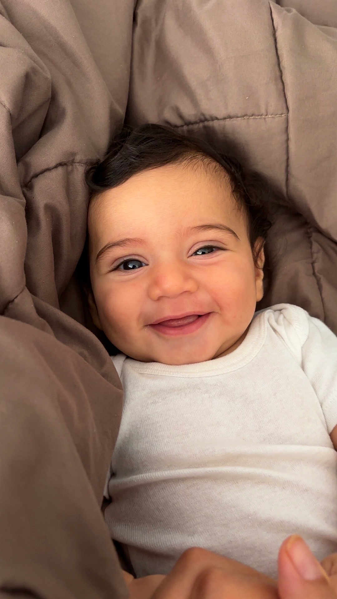 Naïm participe au concours pour gagner de l'argent avec cette photo : baby, smiling, infant, blanket, white_onesie, face, happy, cute, child, portrait, indoors, skin, human, young_child, cozy, expression, warmth, comfort, person, head