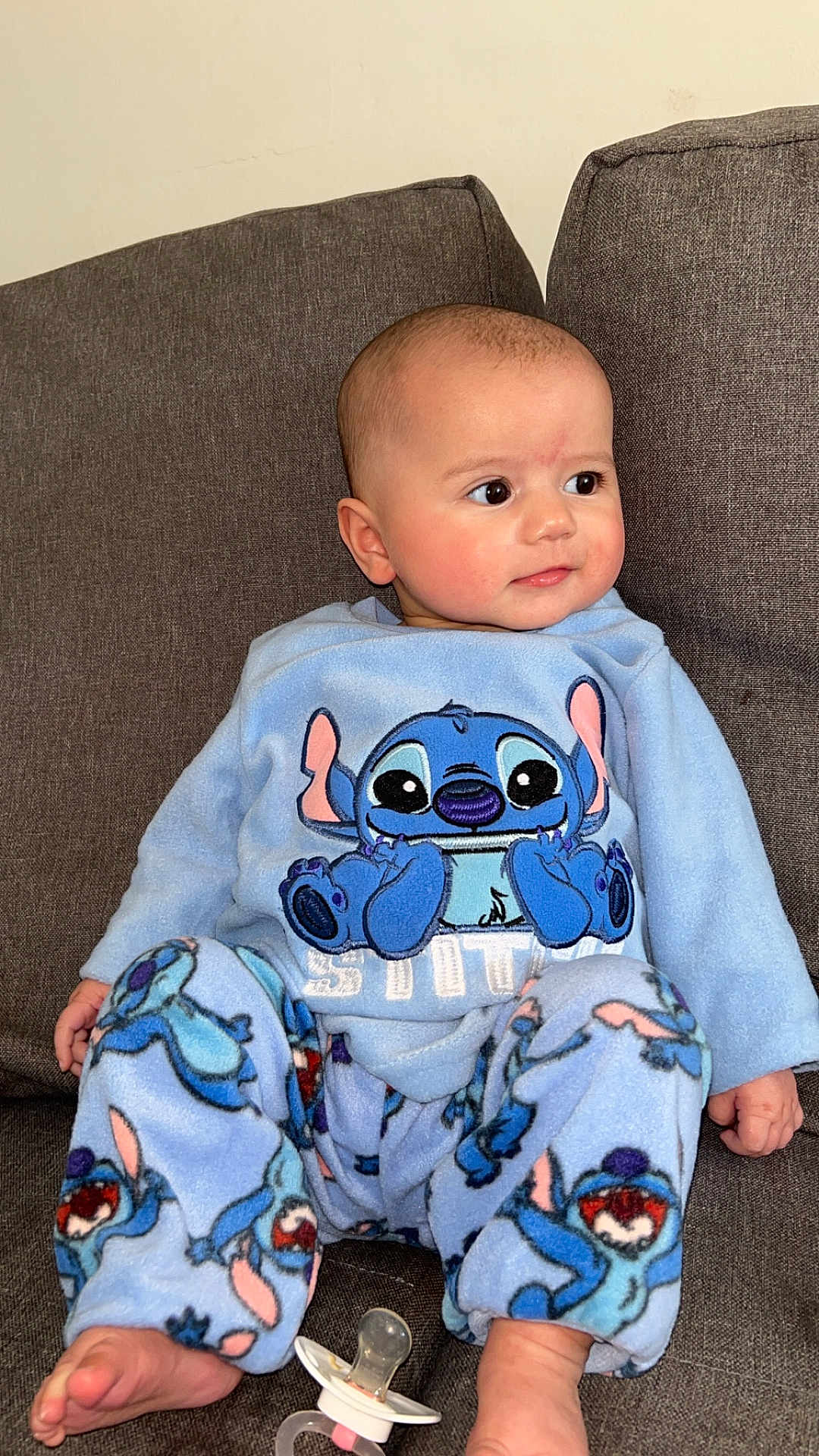 Liyah participe au concours pour gagner de l'argent avec cette photo : baby, child, pajamas, blue_clothing, stitch_character, face, eyes, ear, hand, foot, couch, fabric, pacifier, sitting, indoor, cute, comfort, soft, expression, person