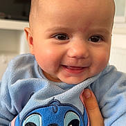 Liyah a rejoint le concours — aidez-le/la à gagner de superbes lots ! baby, blue_clothing, cartoon_character, child, closeup, cute, face, fuzzy_texture, hand, happy, head, indoor, infant, person, portrait, room, smile, stitch, support, warm_clothing