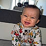 baby, child, smiling, mickey_mouse, cartoon_clothing, indoor, carpet, sitting, holding, bottle, cute, person, young_child, happy, long_sleeve, pants, toy, home, window, furniture