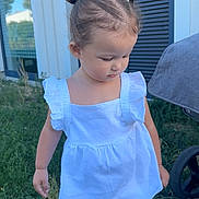 Zélyana participe au concours pour gagner de l'argent avec cette photo : toddler, child, grass, outdoor, white_top, yellow_shorts, ponytails, hair_accessories, building, window, blue_shutters, nature, daylight, person, casual_clothing, barefoot, cute, young_child, summer, greenery