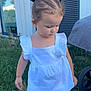 toddler, child, grass, outdoor, white_top, yellow_shorts, ponytails, hair_accessories, building, window, blue_shutters, nature, daylight, person, casual_clothing, barefoot, cute, young_child, summer, greenery