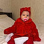 baby, bed, blanket, child, comfortable, cozy, cute, face, fashion, fur_jacket, headband, indoor, infant, pacifier, person, portrait, red_clothing, sitting, socks, white_shoes