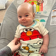 Avery is registered to the contest to win money with this photo: baby, infant, smile, pajamas, elmo, hand, bouncer, cartoon, child, cute, indoor, person, clothing, colorful, seat, comfort, playful, expression, young, happy