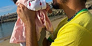 Anaïa a rejoint le concours — aidez-le/la à gagner de superbes lots ! baby, beach, casual, clouds, family, glasses, happy, holding, love, man, outdoor, pink_dress, portrait, sand, short_hair, sky, smiling, sunny, water, yellow_shirt
