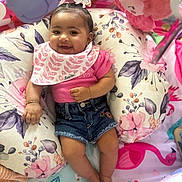 Zeari is registered to the contest to win money with this photo: baby, bracelet, child, colorful, cute, decor, denim_shorts, feet, floral_cushion, happy, headband, indoors, infant, pink_shirt, play_area, plush_toy, portrait, sitting, smiling, soft_toys