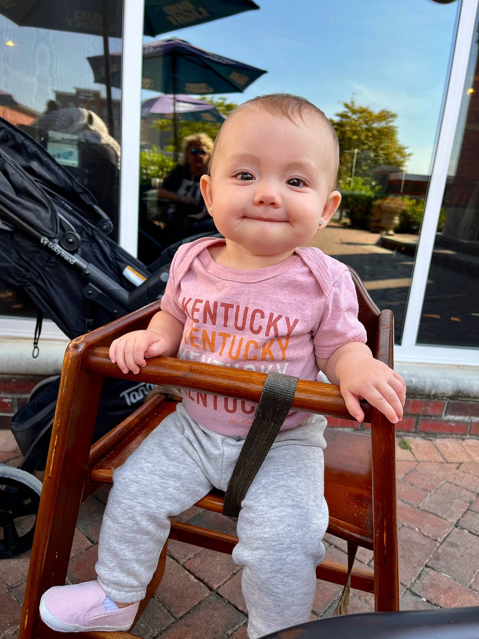Ella is registered to the contest to win money with this photo: baby, baby_toddler_clothing, chair, child, city, fun, happy, joy, leisure, outdoor_furniture, people, person, public_space, recreation, shorts, sitting, sky, smile, standing, toddler