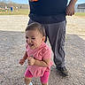 toddler, child, person, outdoor, gravel, pink_clothing, shoes, smiling, happy, adult, hand, cup, sky, grass, trees, people, casual_clothing, daylight, fun, playing