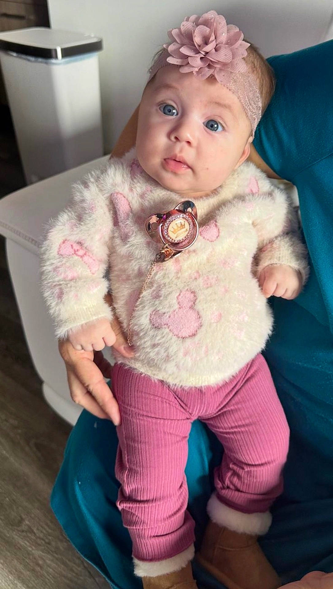 adult, baby, blue_eyes, boots, chair, child, cozy, cute, floor, flower, hand, headband, indoor, pants, person, pink, portrait, seated, sweater, trash_bin