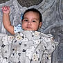 baby, blanket, sheep_pattern, carpet, soft_texture, child, infant, raised_arm, lying_down, cozy, indoors, cute, sleepwear, sleeping_area, resting, portrait, young_child, warm, comfort, peaceful