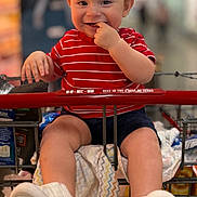 Jeremiah is registered to the contest to win money with this photo: baby, child, toddler, grocery_cart, supermarket, shopping, smiling, happy, portrait, red_shirt, striped_shirt, white_shoes, sneakers, sitting, finger_in_mouth, indoor, groceries, shopping_cart, closeup, family_photo