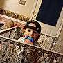 Joseph joined the competition — help win amazing prizes! toddler, child, indoor, playpen, toy, cap, hat, chewing, curious, furniture, door, wall, light_switch, baby, clothing, plastic, stuffed_animal, floor, person, home