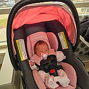 Amy is registered to the contest to win money with this photo: newborn, baby, pacifier, car_seat, pink, black, infant, indoors, window, parking_lot, blanket, clothing, child, seat_belt, safety, resting, cute, infant_care, baby_gear, pacifier_clip