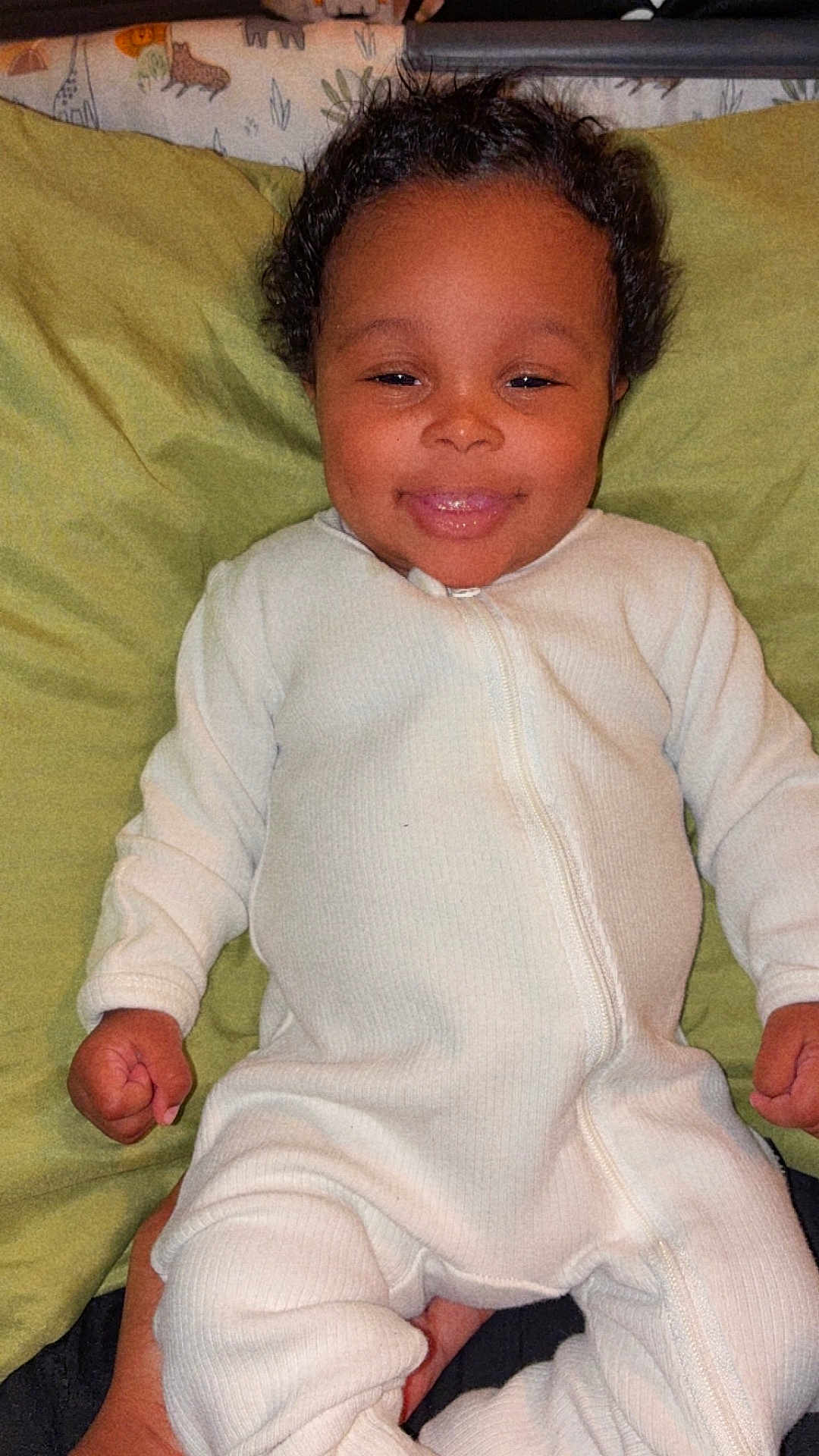Kennedi Antoine is registered to the contest to win money with this photo: baby, child, infant, onesie, smile, face, curly_hair, pillow, green_pillow, sleepwear, cute, happy, lying_down, indoor, person, young_child, cozy, portrait, hands, resting