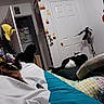 Ink is registered to the contest to win money with this photo: animal, banana_hat, bed, blanket, cat, colorful, cozy, decor, door, furniture, helmet, indoor, mario_decals, pillow, poster, relaxing, resting, room, scooter, wall