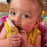 Malakai is registered to the contest to win money with this photo: baby, child, toy, yellow_clothing, indoor, face, hands, chewing, colorful_background, playful, infant, curious, person, closeup, seat, bright_colors, pink, pattern, cute, expression