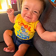 Malakai is registered to the contest to win money with this photo: baby, child, smiling, yellow_shirt, tank_top, sitting, couch, indoor, happy, cute, infant, casual_clothing, shorts, barefoot, portrait, light, home, relaxed, funny_expression, person