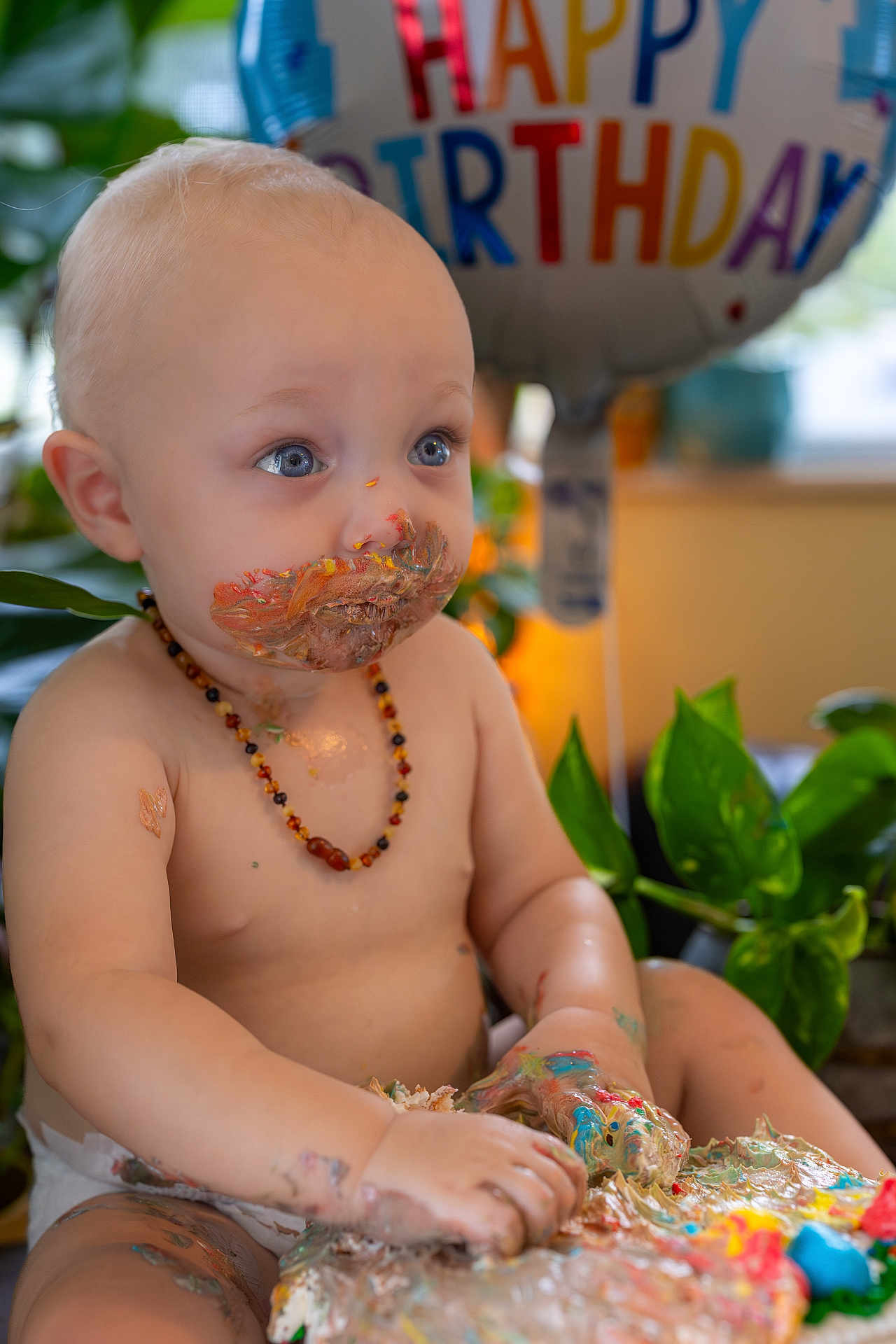 James joined the competition — help win amazing prizes! baby, birthday, cake, messy, frosting, blue_eyes, diaper, necklace, balloon, celebration, indoor, plants, child, happy, cute, portrait, sitting, food, colorful, smudged