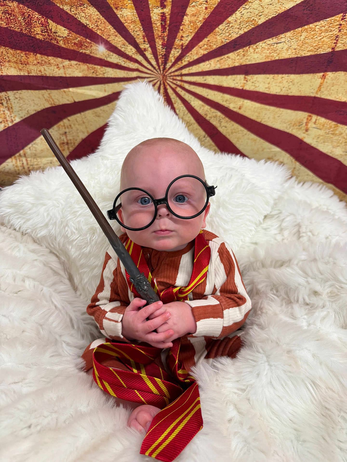 Axel joined the competition — help win amazing prizes! baby, child, glasses, wand, striped_clothing, red_tie, white_blanket, fluffy, portrait, indoor, magical, costume, cute, serious_expression, sitting, toy, background_pattern, round_glasses, infant, closeup