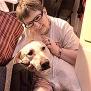 Cyder joined the competition — help win amazing prizes! person, dog, glasses, smile, indoor, pet, light, casual_clothing, floor, coat, jewelry, short_hair, hand, face, companion, comfort, relaxation, domestic, friendly, affection