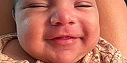 Athena is registered to the contest to win money with this photo: baby, smiling, close_up, face, infant, child, clothing, floral, pattern, happy, skin, person, portrait, cute, young, resting, apparel, head, cheeks, baby_girl