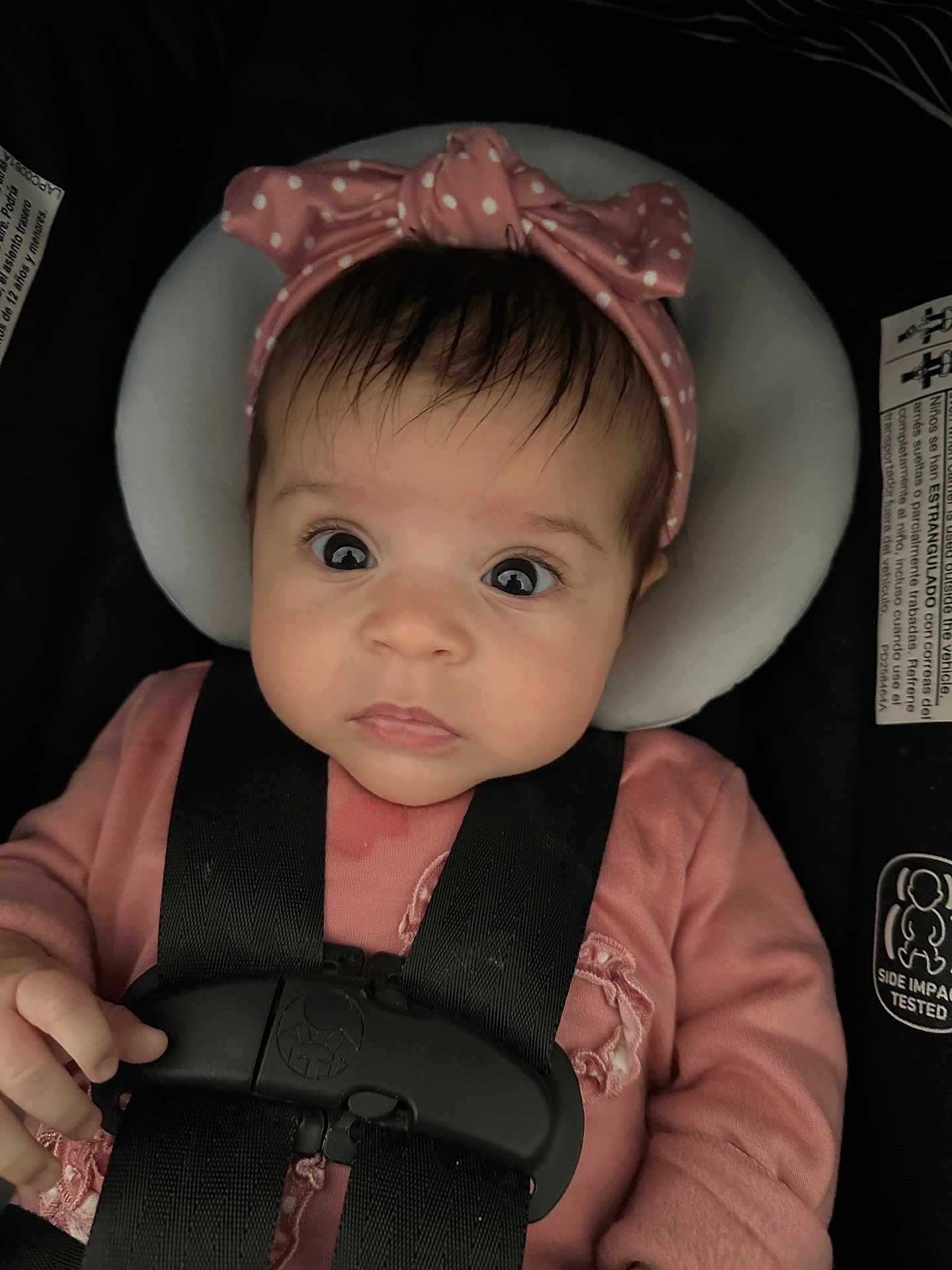 Marie joined the competition — help win amazing prizes! baby, infant, car_seat, headband, pink_clothing, straps, child, face, eyes, portrait, sitting, cute, young_child, safety, seat_belt, clothing, hand, expression, indoors, person