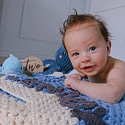 Lennox is registered to the contest to win money with this photo: baby, infant, smile, face, blue_eyes, crocheted_blanket, plush_toys, octopus_toy, dolphin_toy, wooden_sign, two_months, indoor, floor, cute, child, portrait, happy, skin, hair, playful