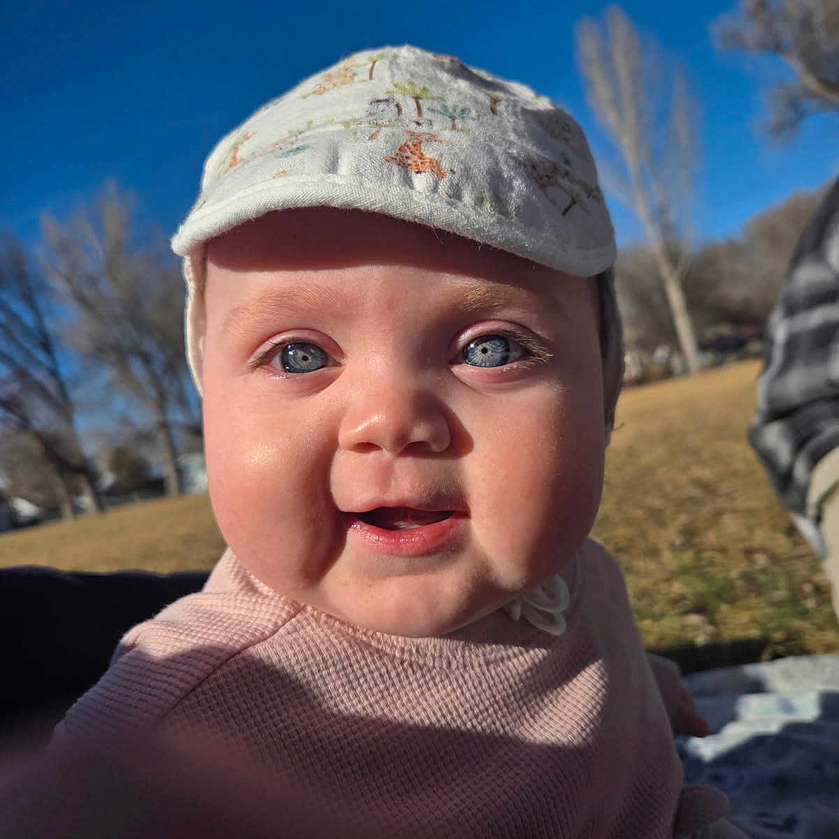 Siryna joined the competition — help win amazing prizes! baby, blue_eyes, cap, cheeks, child, clothing, cute, daytime, face, grass, happy, infant, nature, outdoor, park, person, portrait, smile, sunlight, trees