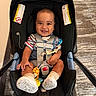 baby, baby_feet, car_seat, carpet, child, happy, harness, indoor, infant, looking_at_camera, pacifier, photography, portrait, safety_harness, seated, smile, smiling, socks, striped_shirt, toy