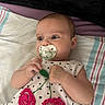 baby, bedding, blanket, child, crocheted_flowers, cute, dress, face, green_toy, hands, head, indoor, infant, lying_down, pacifier, polka_dots, portrait, striped_blanket, toy, wide_eyes