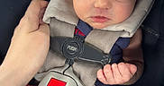 Arya is registered to the contest to win money with this photo: newborn, baby, sleeping, infant, car_seat, safety_harness, bow, headband, pacifier, caregiver, hand, portrait, close_up, indoors, vehicle, blanket, clothing, socks, peaceful, family