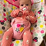 baby, child, infant, portrait, sitting, bouncer, baby_chair, pink_clothing, pacifier, minnie_mouse, disney, colorful, indoor, polka_dots, hearts, stars, floral_pattern, carpet, toys, happy