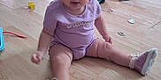 Isabella is registered to the contest to win money with this photo: baby, child, indoor, floor, toy, sippy_cup, bow, pink_shoes, purple_clothing, wooden_floor, playtime, cute, sitting, curious, headband, infant, person, room, scattered_toys, footwear