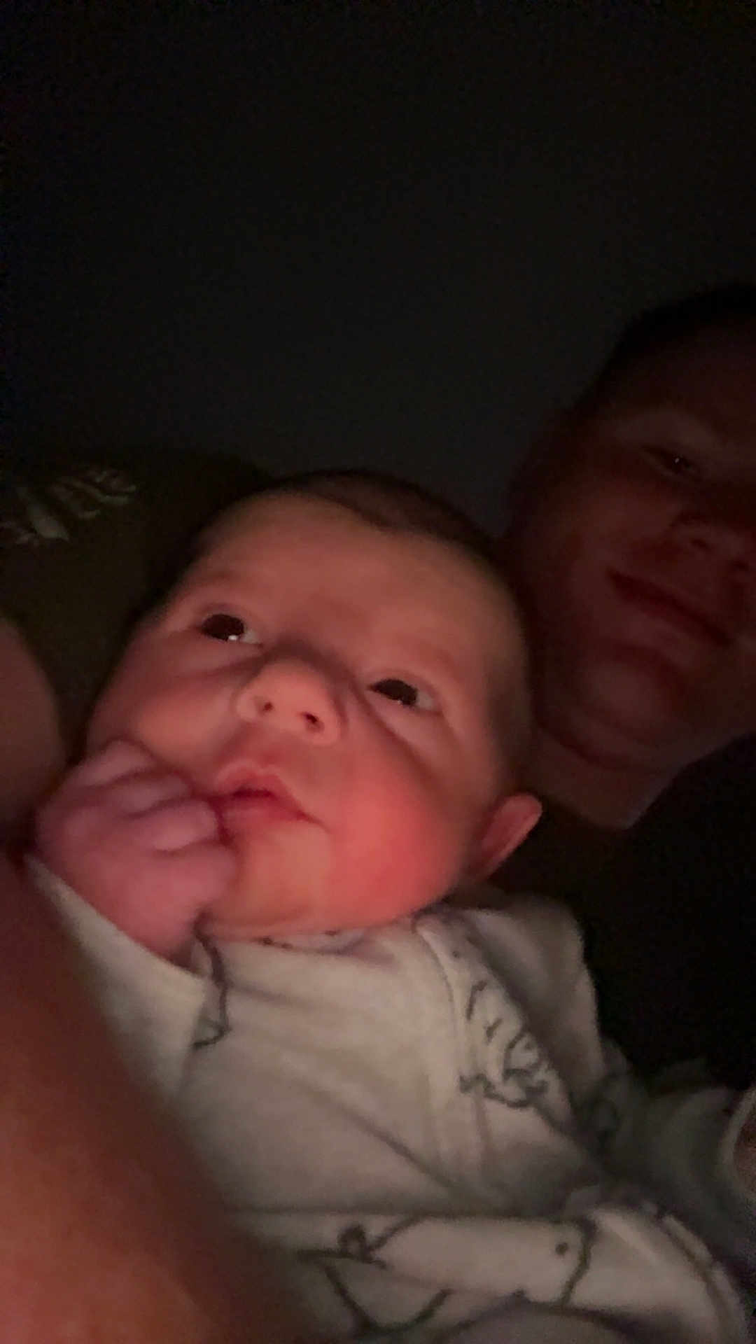 Archer is registered to the contest to win money with this photo: baby, infant, person, face, adult, portrait, closeup, expression, hand, sleepwear, night, dark, cozy, cuddle, smile, skin, head, eyes, family, love