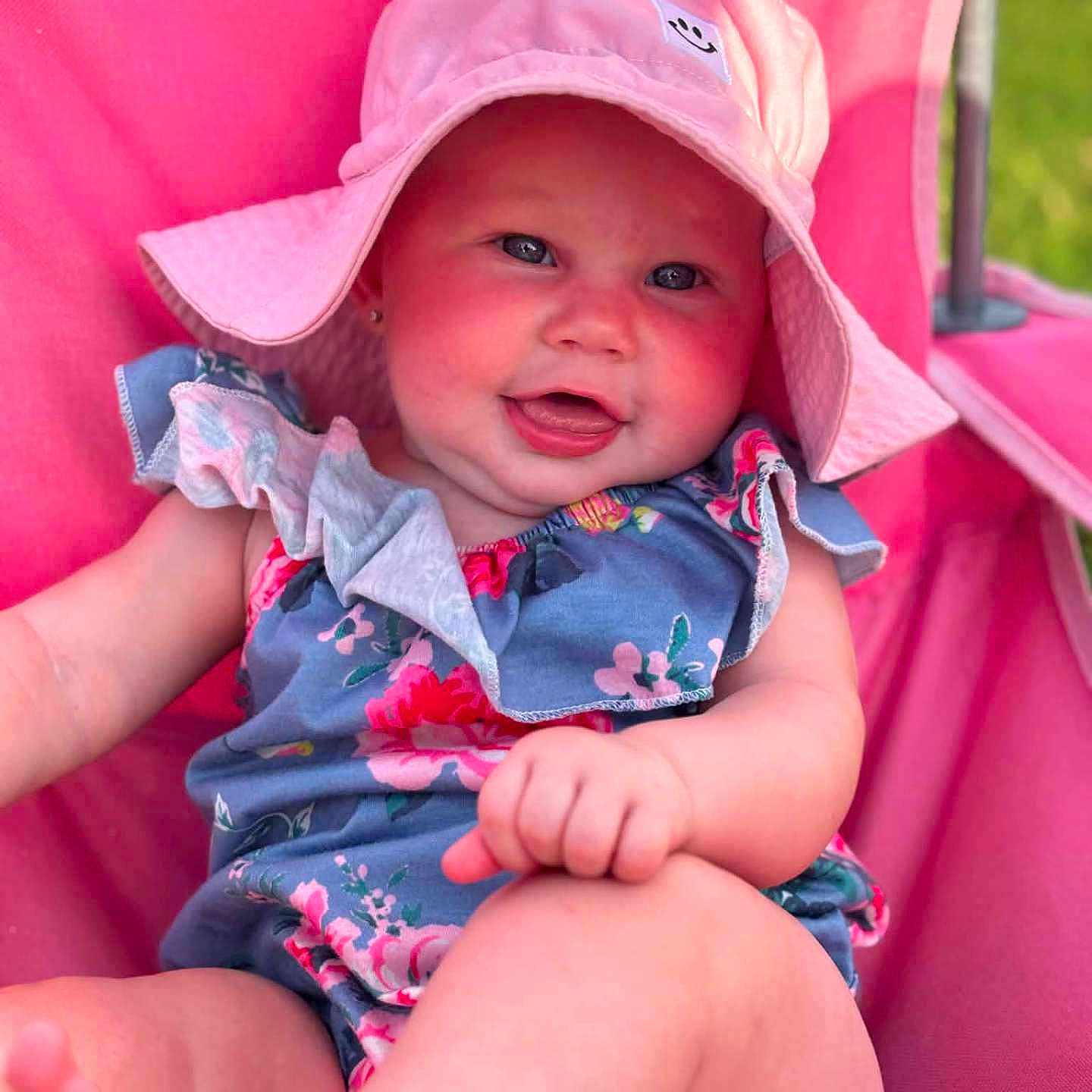 Hazel is registered to the contest to win money with this photo: baby, child, smiling, hat, pink, blue, floral, outdoor, sunhat, cute, happy, person, portrait, sitting, summer, skin, face, clothing, babywear, foot