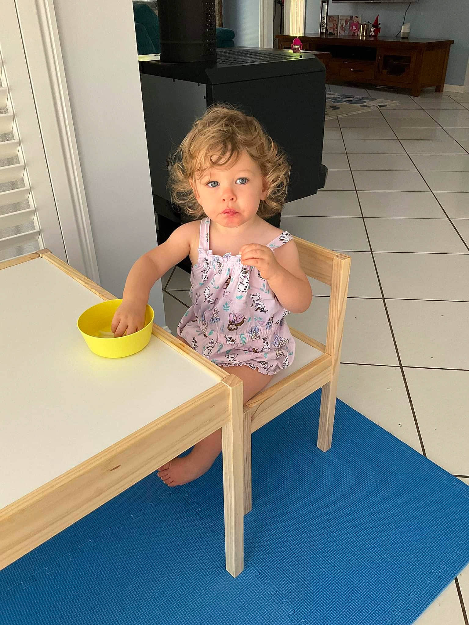 Leah is registered to the contest to win money with this photo: baby_toddler_clothing, chair, child, comfort, floor, flooring, fun, hardwood, home_appliance, house, human_leg, leisure, person, play, room, sitting, t_shirt, table, toddler, wood