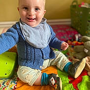 Rupert is registered to the contest to win money with this photo: baby, bib, blue_sweater, child, colorful, cute, happy, indoor, infant, laundry_basket, nursery, patchwork_quilt, playful, reaching_out, rocket_design, sitting, smiling, socks, soft_shoes, toy