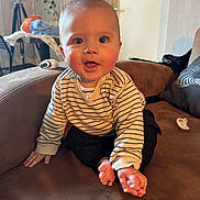 Milan participe au concours pour gagner de l'argent avec cette photo : baby, child, striped_sweater, couch, indoor, happy, smiling, toes, hands, pacifier, furniture, home, person, face, cute, seated, living_room, casual, infant, expression