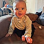 baby, child, striped_sweater, couch, indoor, happy, smiling, toes, hands, pacifier, furniture, home, person, face, cute, seated, living_room, casual, infant, expression