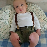 Kasyn is registered to the contest to win money with this photo: baby, infant, child, portrait, lying_down, sitting, suspenders, white_shirt, green_shorts, socks, pillow, blanket, crib, nursery, indoor, face, eyes, curious, patterned_fabric, photography