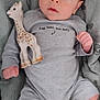 baby, infant, toy, giraffe, onesie, blanket, pattern, sock, cute, child, soft, indoors, portrait, lying_down, expression, curious, small_hand, baby_clothes, colorful, peaceful