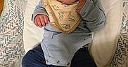Dexter joined the competition — help win amazing prizes! baby, infant, bib, bottle, feeding, socks, clothing, dinosaur_pattern, cushion, seat, indoor, person, cute, child, young, portrait, expression, hand, footwear, relaxing