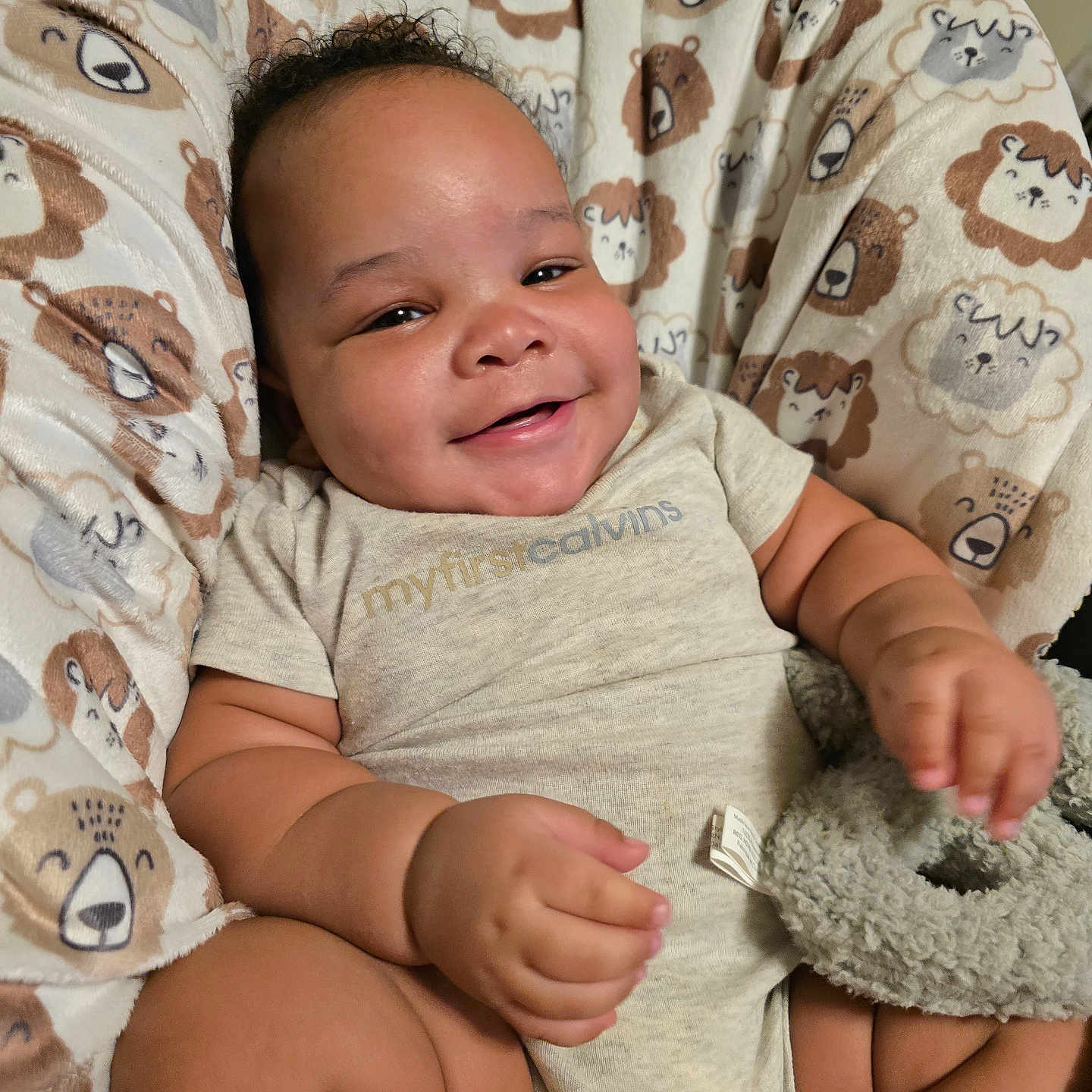 Dexter is registered to the contest to win money with this photo: baby, smiling, infant, onesie, toy, plush_toy, chair, bear_pattern, cute, happy, child, indoor, comfort, soft_fabric, relaxed, portrait, skin, short_hair, seated, cozy