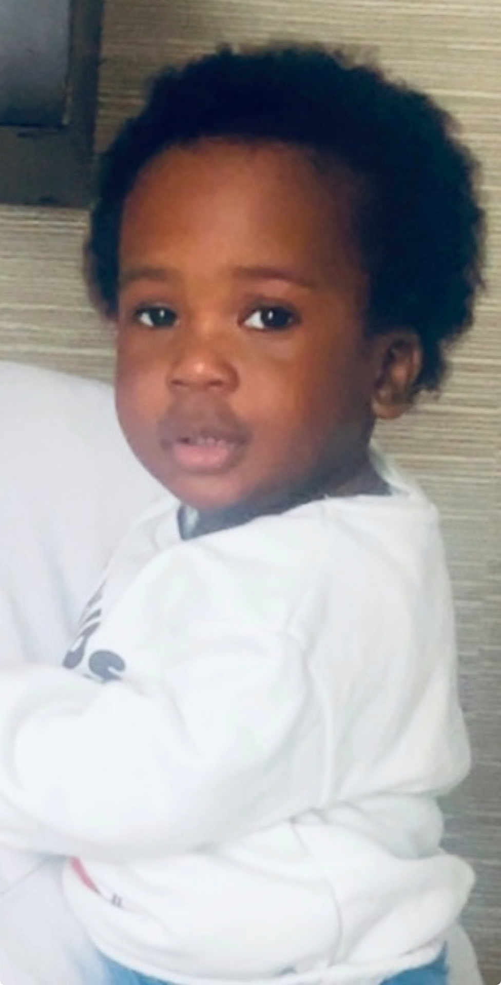 Kamal participe au concours pour gagner de l'argent avec cette photo : casual, child, closeup, curly_hair, cute, expression, face, head_and_shoulders, human, indoor, looking_at_camera, natural, neutral_background, person, portrait, sitting, soft_lighting, white_clothing, young_child, young_person