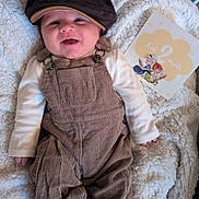 Abygaël participe au concours pour gagner de l'argent avec cette photo : baby, smiling, corduroy_overalls, hat, blanket, milestone_card, footwear, infant, clothing, happy, indoor, portrait, cute, child, baby_shoes, face, person, resting, young_child, soft_texture