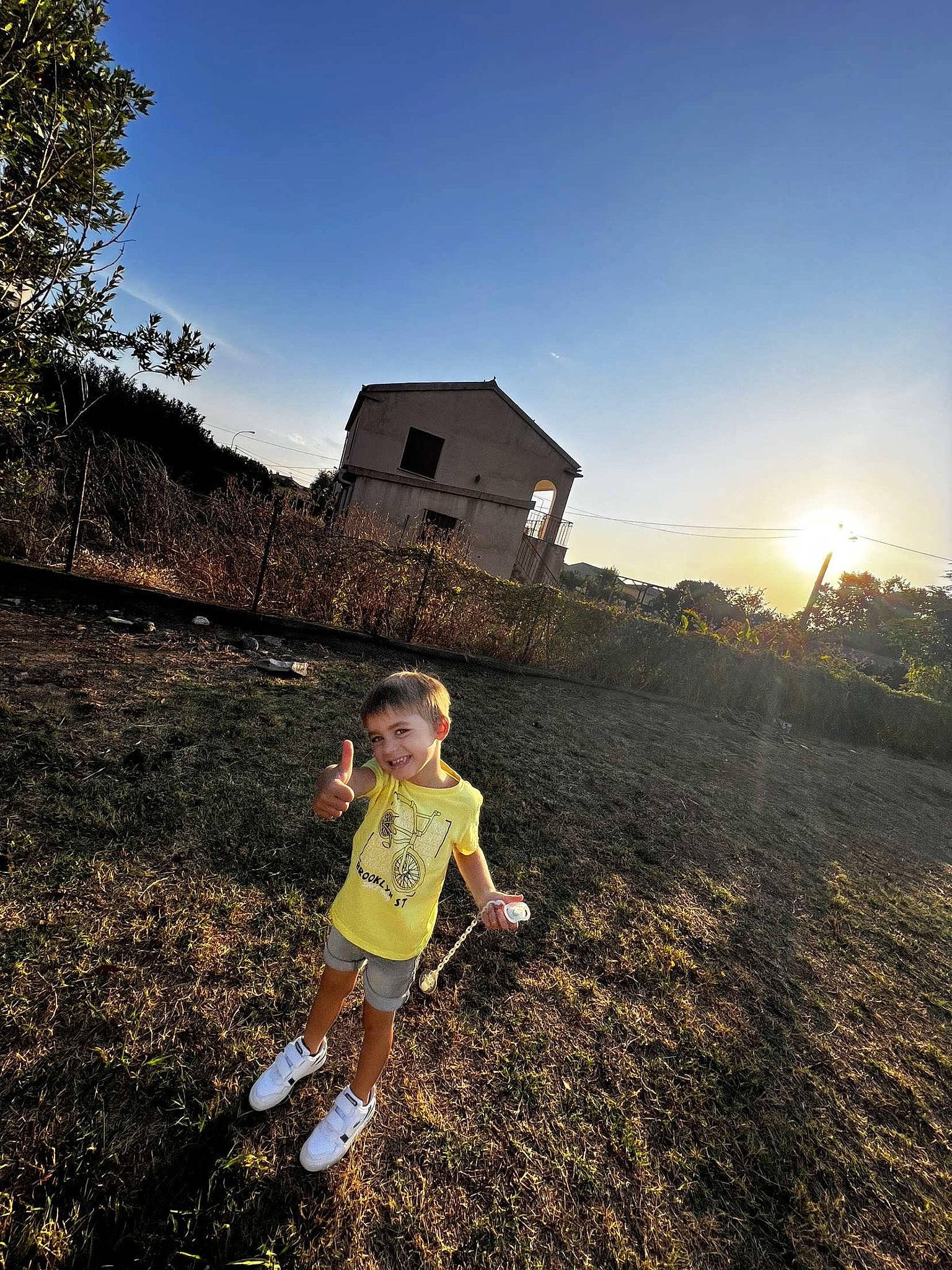 Nohlan a rejoint le concours — aidez-le/la à gagner de superbes lots ! asphalt, flash_photography, fun, grass, grassland, happy, hill, horizon, house, joy, landscape, leaf, leisure, light, people_in_nature, person, sky, standing, sunlight, toddler